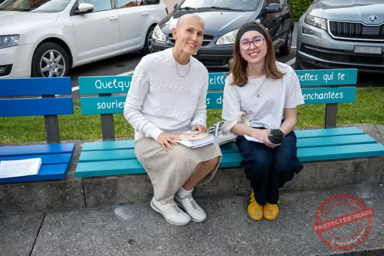 Floriane Eyota Nakan assise sur le banc calligraphié de sa poésie vibratoire en compagnie d'une journaliste pour échanger autour de son livre l'UN-puissance des maux.
